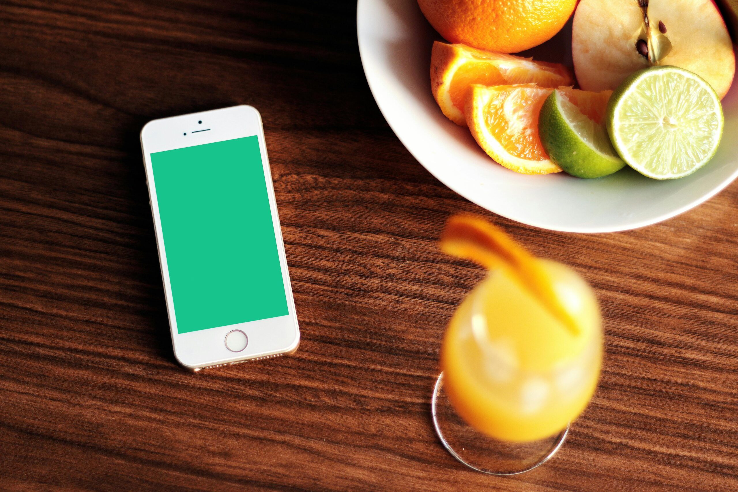 Mockup of a smartphone with fresh citrus fruits and juice on a wooden table.