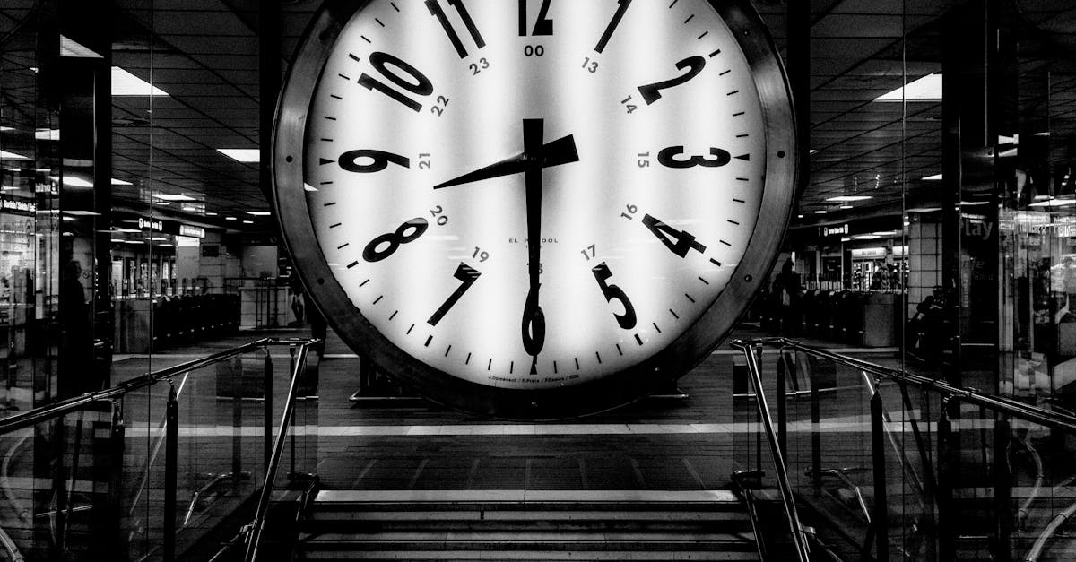 Monochrome image of a large clock at a train station, conveying the passage of time.