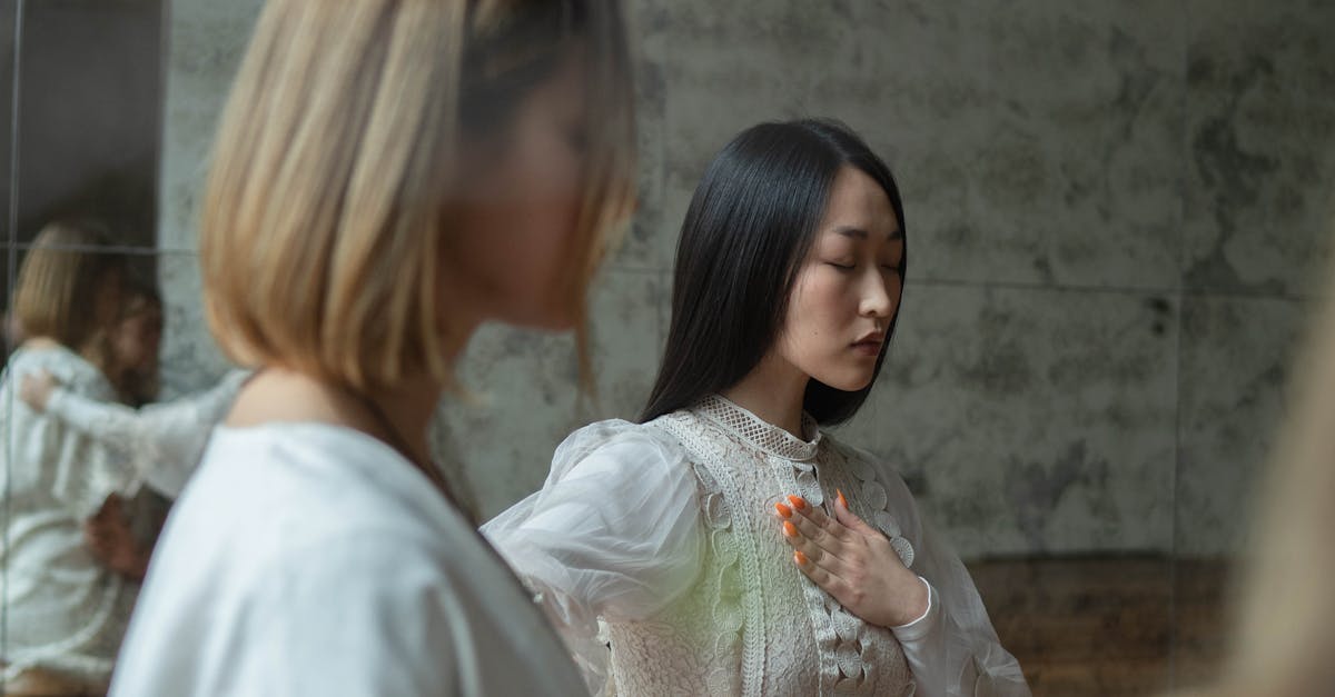 Two women practicing meditation indoors, conveying tranquility and focus in a serene setting.