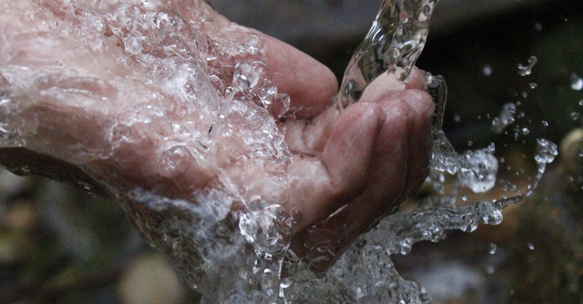 Close-up of a human hand under a stream of clear, flowing water.